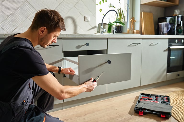 Man assembling kitchen drawer in modern cabinet using screwdriver
